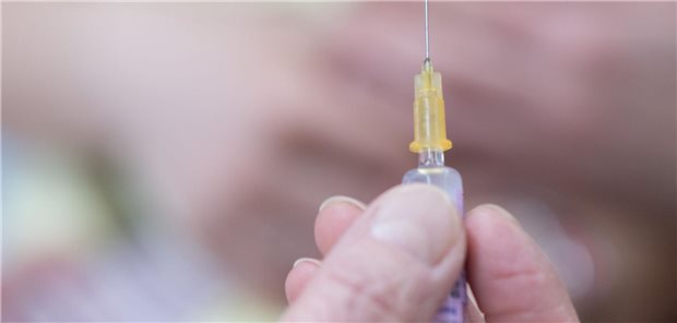 Eine Kinderärztin hält bei einer Kinderimpfung gegen Meningokokken eine Spritze hoch.